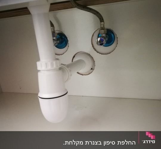 צינור ניקוז לבן מתחת לכיור עם חיבורים
